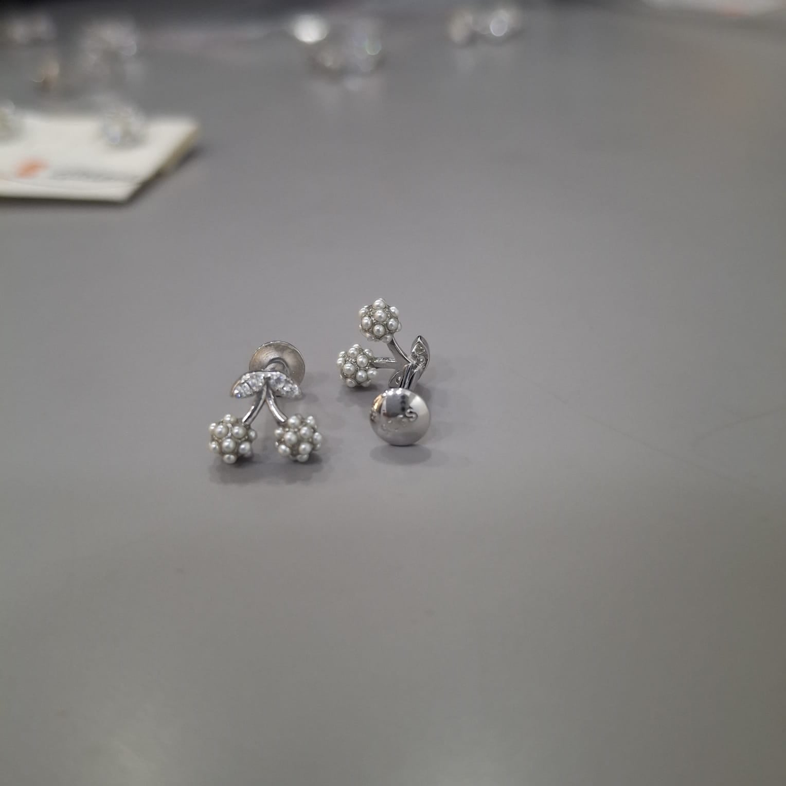 925 sterling silver stud earrings with stone-lined leaves and twin polished cherry clusters, side view.