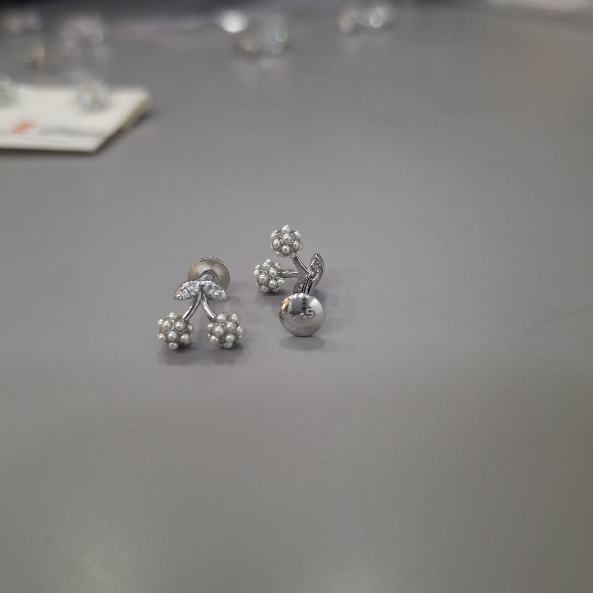 925 sterling silver stud earrings with stone-lined leaves and twin polished cherry clusters, side view.