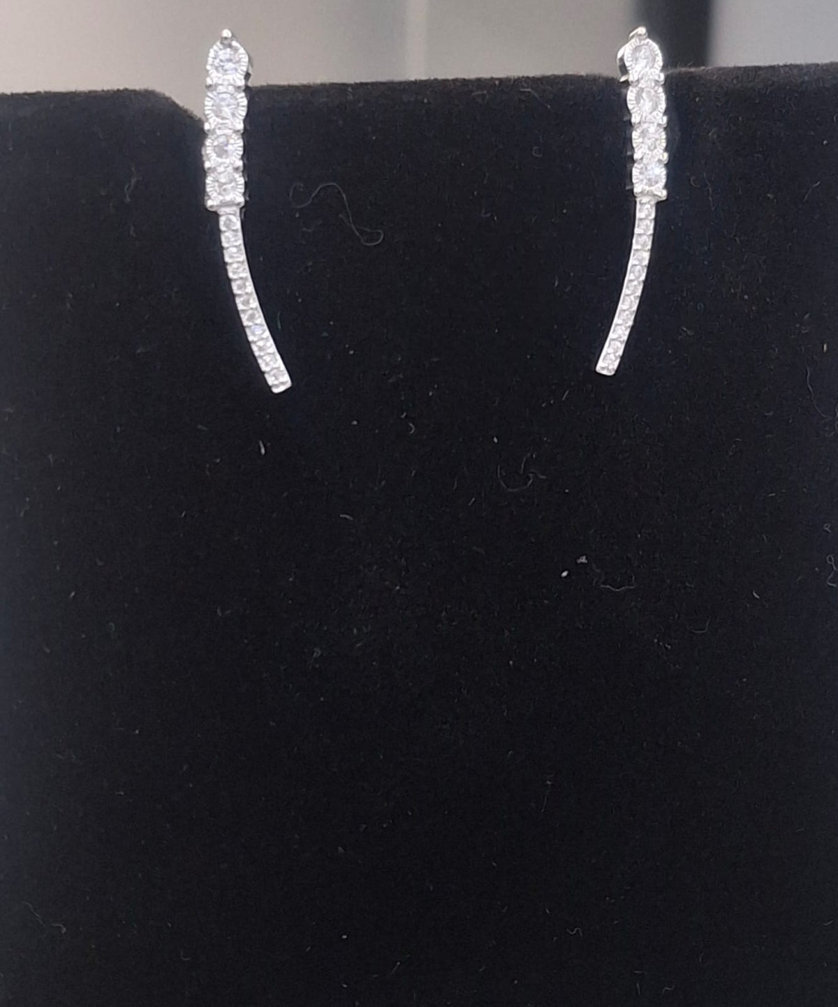 925 sterling silver ear climbers with four graduated round clear stones and a slim curved accent line.