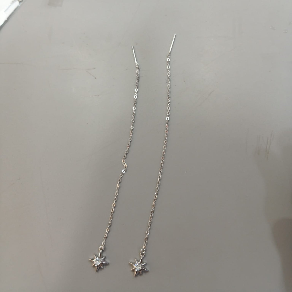 925 sterling silver Sui Dhaga earring with eight-point starburst and clear centre, shown from front and side.